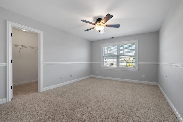 unfurnished bedroom featuring a closet, a walk in closet, carpet floors, and ceiling fan