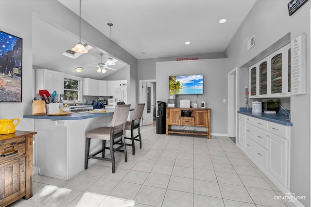 kitchen featuring lofted ceiling with beams, a kitchen breakfast bar, kitchen peninsula, ceiling fan, and white cabinetry