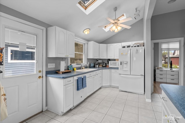 kitchen with vaulted ceiling with skylight, white appliances, ceiling fan, sink, and white cabinets