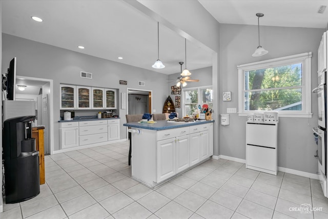 kitchen with ceiling fan, white cabinets, light tile patterned flooring, and vaulted ceiling