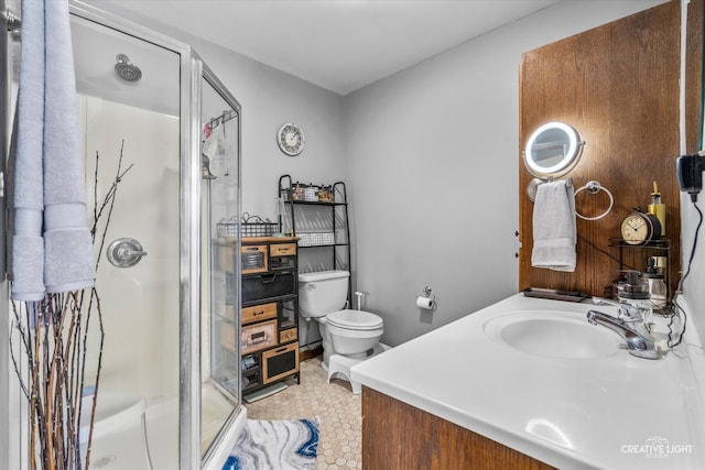 bathroom featuring vanity, a shower with shower door, and toilet