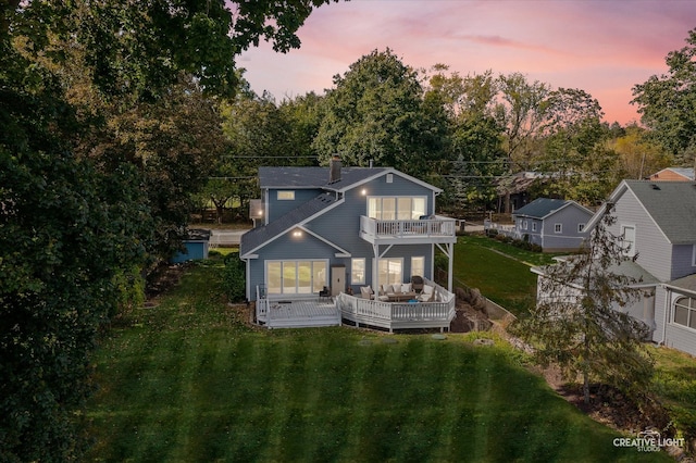 back house at dusk featuring outdoor lounge area, a balcony, and a yard