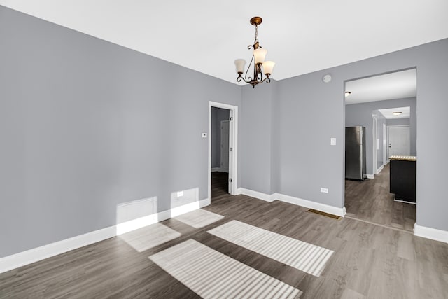 unfurnished room featuring a chandelier and hardwood / wood-style floors