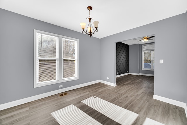 spare room with ceiling fan with notable chandelier and wood-type flooring