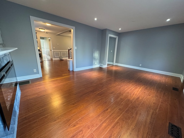 unfurnished living room featuring dark wood-type flooring and a brick fireplace