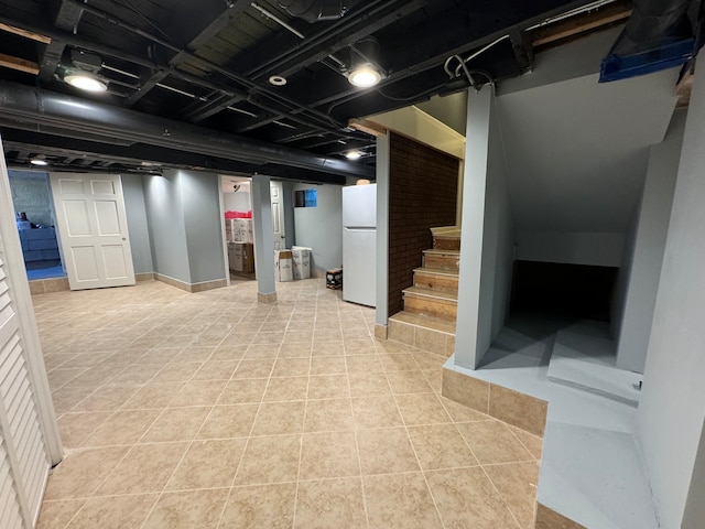 basement with light tile patterned flooring and white refrigerator