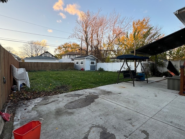 patio terrace at dusk featuring an outbuilding and a lawn