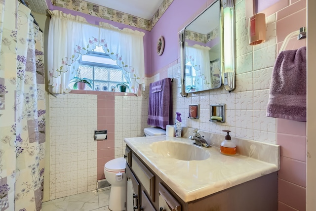 bathroom featuring vanity, toilet, and tile walls