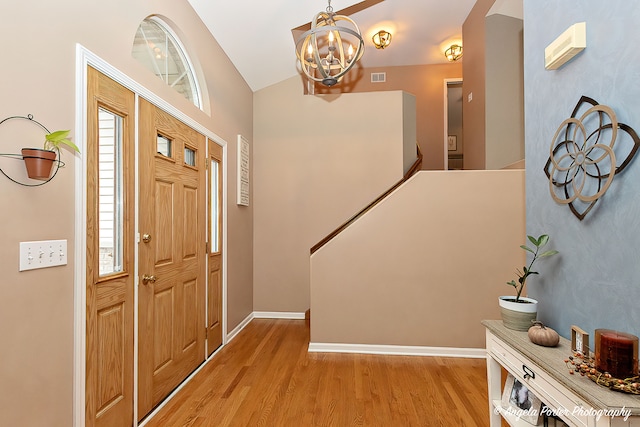 entryway with light hardwood / wood-style floors, vaulted ceiling, and a notable chandelier