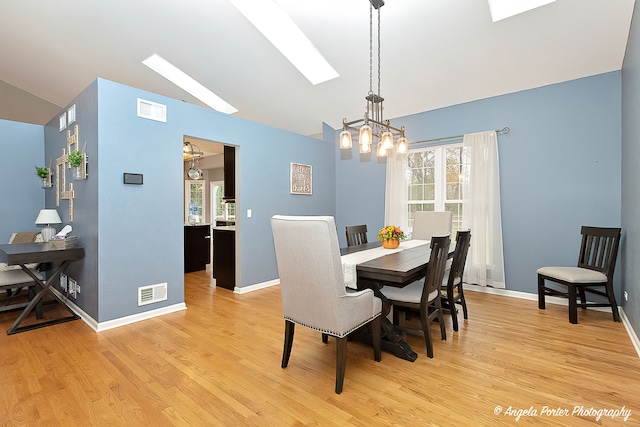 dining room featuring vaulted ceiling, an inviting chandelier, and light hardwood / wood-style flooring