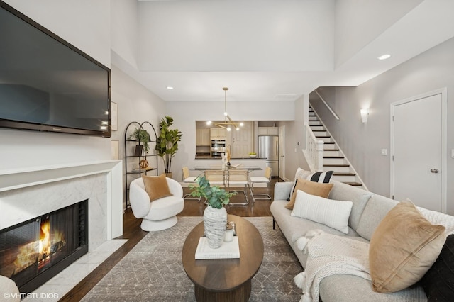 living area featuring a high end fireplace, wood finished floors, recessed lighting, and stairway