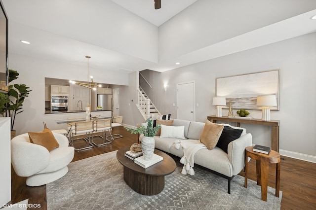 living area with dark wood finished floors, baseboards, and stairway