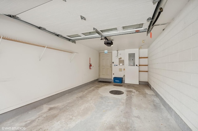 garage featuring electric panel, a garage door opener, and concrete block wall