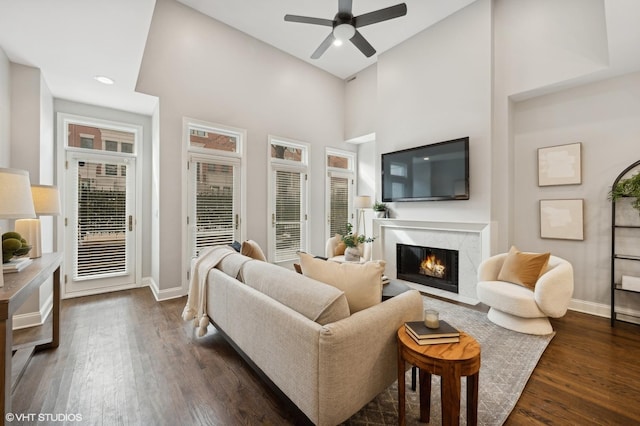 living room featuring dark wood finished floors, baseboards, a fireplace, and ceiling fan