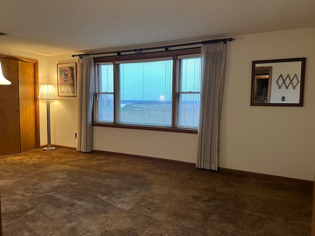 spare room featuring dark colored carpet and a textured ceiling