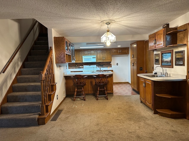 kitchen with pendant lighting, light colored carpet, white appliances, and sink