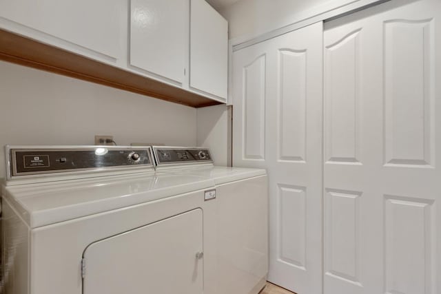 clothes washing area with washer and dryer and cabinets