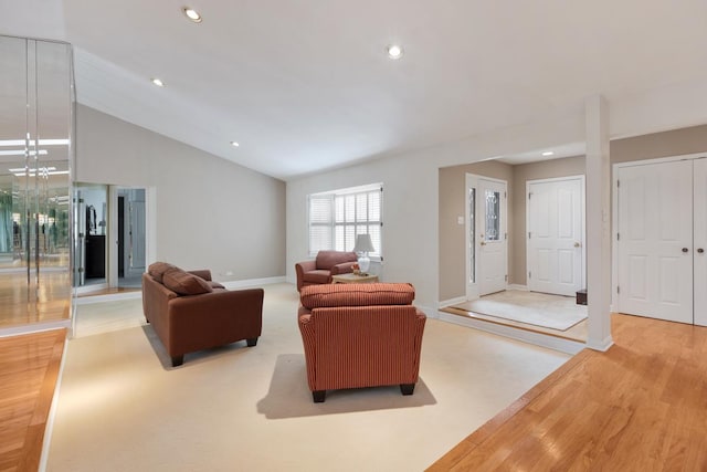 living room featuring vaulted ceiling, light wood-type flooring, and decorative columns