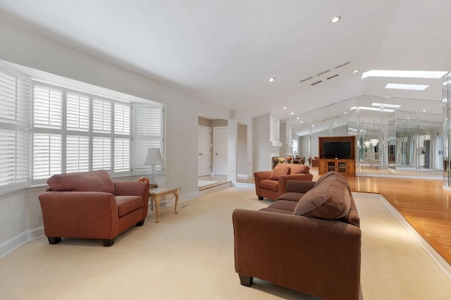 living room featuring vaulted ceiling with skylight and light colored carpet