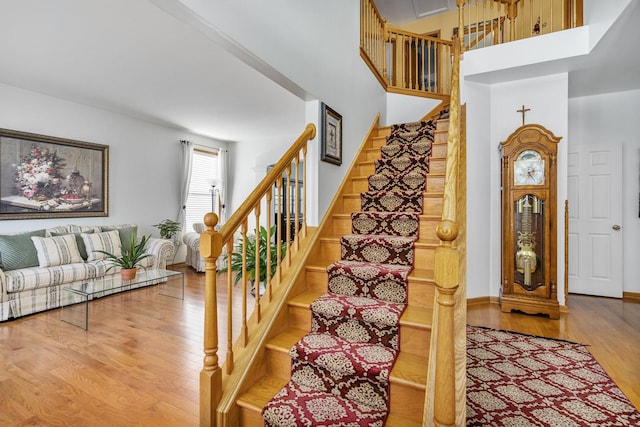 stairs featuring a towering ceiling and wood-type flooring