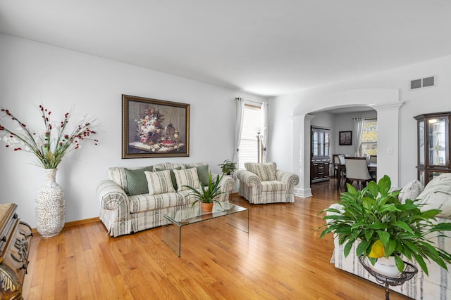 living room with wood-type flooring, decorative columns, and a wealth of natural light