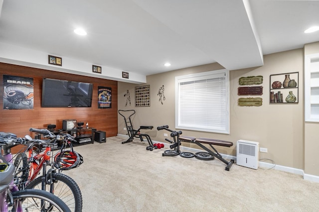 exercise area featuring light colored carpet and wood walls