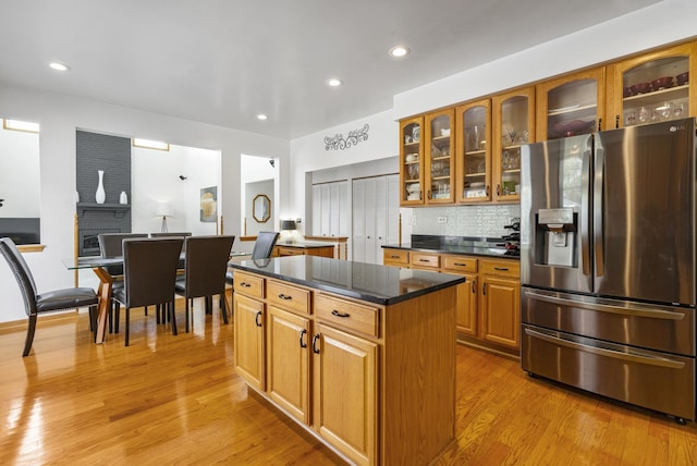 kitchen featuring backsplash, a center island, stainless steel fridge with ice dispenser, and light wood-type flooring