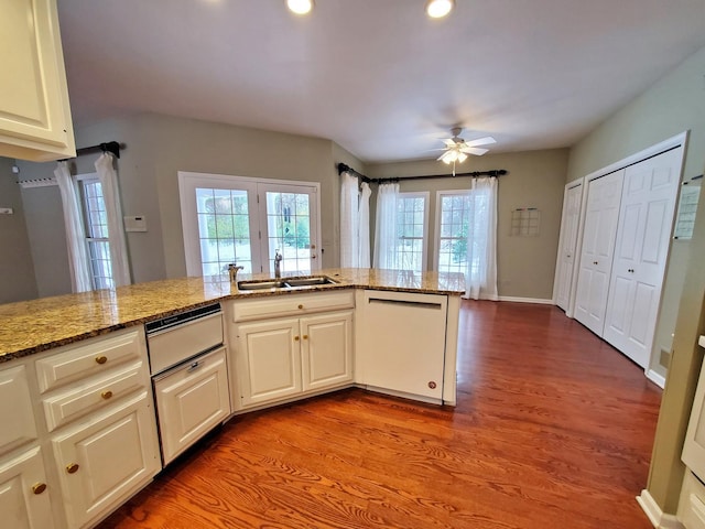 kitchen featuring dishwasher, light stone counters, a sink, and light wood-style floors