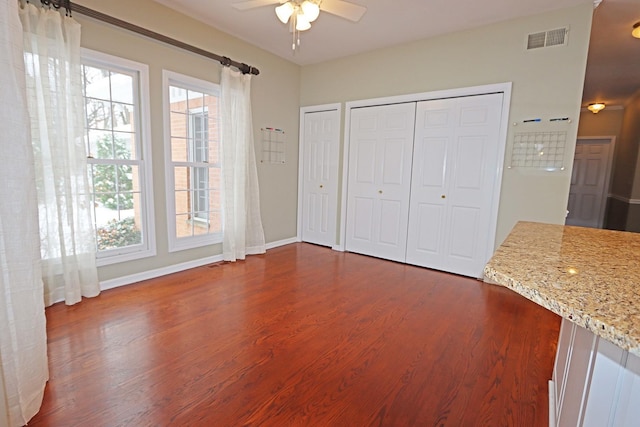 interior space featuring multiple closets, multiple windows, visible vents, and dark wood-style flooring