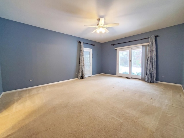 spare room with light carpet, ceiling fan, and baseboards