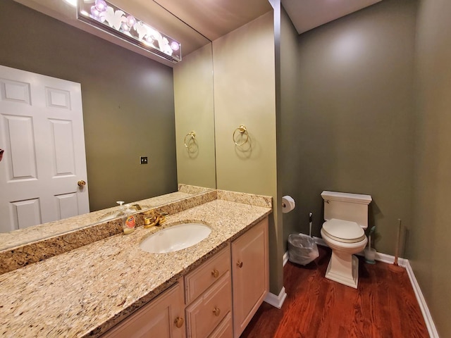 bathroom with baseboards, vanity, toilet, and wood finished floors