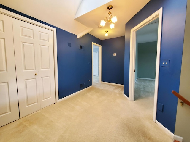 unfurnished bedroom with a closet, light colored carpet, visible vents, a chandelier, and baseboards