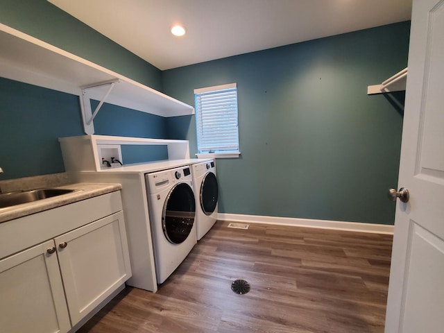 clothes washing area with dark wood-style flooring, a sink, baseboards, independent washer and dryer, and cabinet space