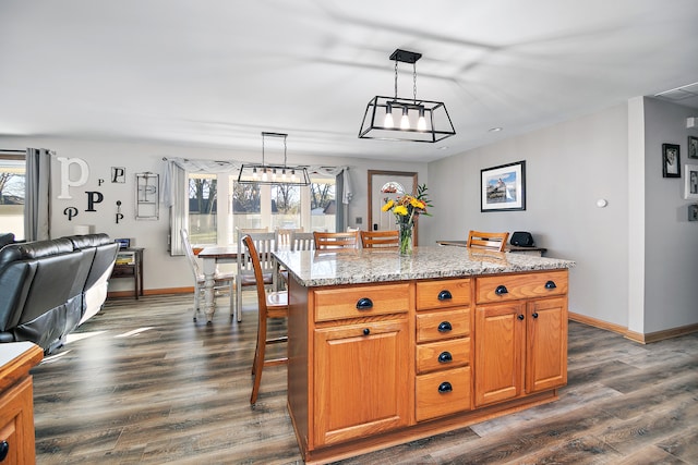 kitchen featuring a kitchen breakfast bar, hanging light fixtures, light stone countertops, a kitchen island, and dark hardwood / wood-style flooring