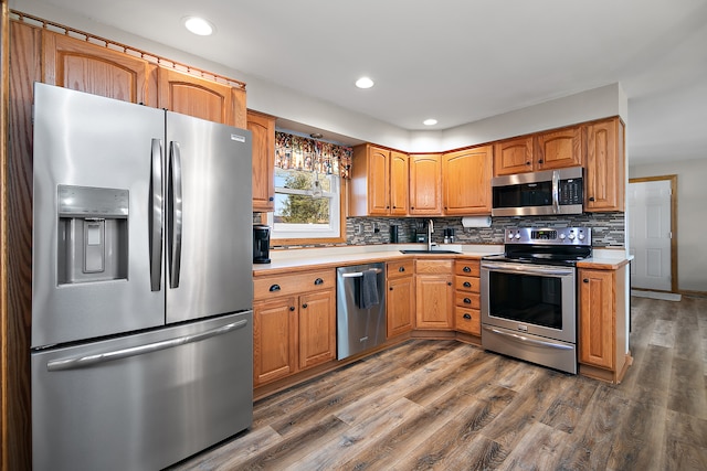 kitchen with sink, appliances with stainless steel finishes, dark hardwood / wood-style flooring, and backsplash