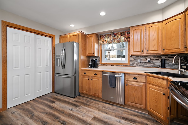 kitchen featuring appliances with stainless steel finishes, backsplash, dark wood-type flooring, and sink