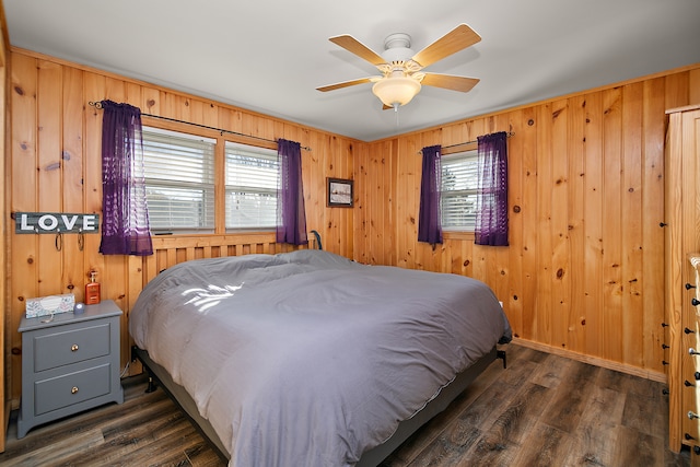 bedroom featuring dark hardwood / wood-style flooring, multiple windows, wood walls, and ceiling fan