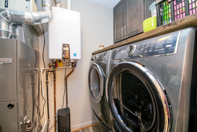 laundry room featuring washer and dryer, tankless water heater, hardwood / wood-style flooring, and cabinets