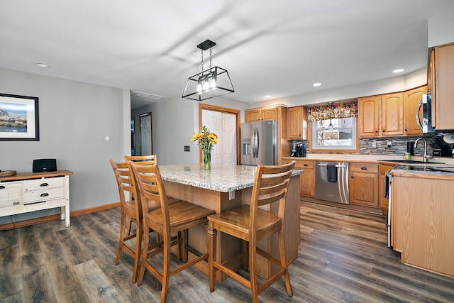 kitchen featuring appliances with stainless steel finishes, sink, decorative light fixtures, dark hardwood / wood-style floors, and a kitchen island