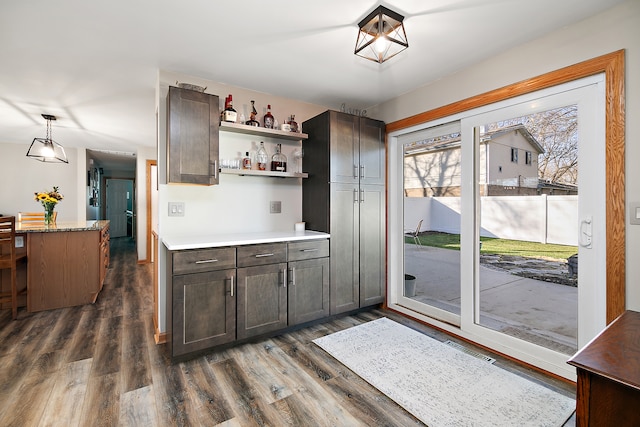 kitchen with dark hardwood / wood-style flooring, a center island, pendant lighting, and dark brown cabinets