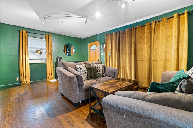 living room with dark hardwood / wood-style flooring, rail lighting, and plenty of natural light