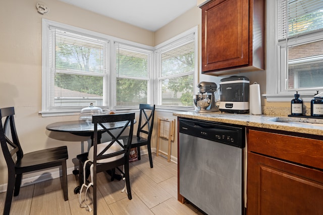 kitchen featuring light stone counters, dishwasher, and sink