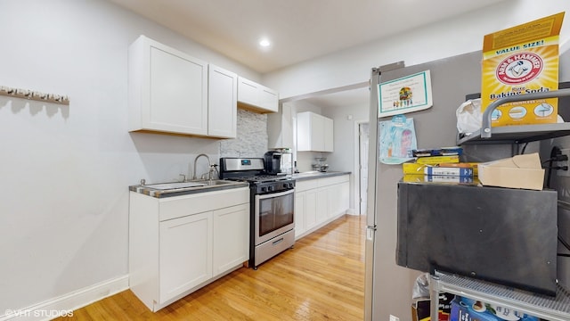 kitchen with white cabinets, sink, light hardwood / wood-style flooring, and stainless steel range with gas stovetop