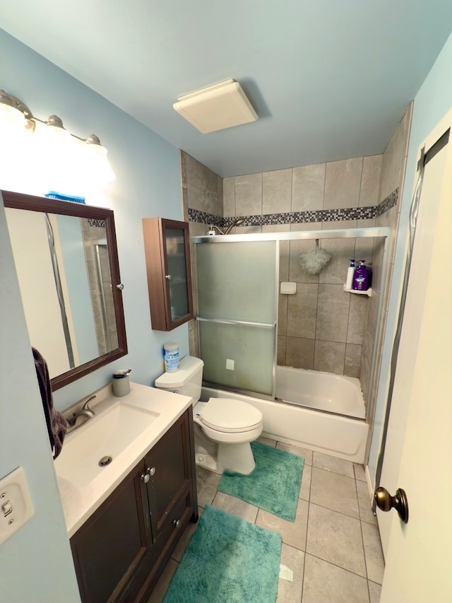 full bathroom featuring shower / bath combination with glass door, vanity, tile patterned flooring, and toilet