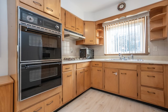 kitchen featuring decorative backsplash, sink, double oven, and light hardwood / wood-style flooring