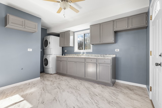 kitchen with stacked washer and dryer, ceiling fan, gray cabinetry, and sink