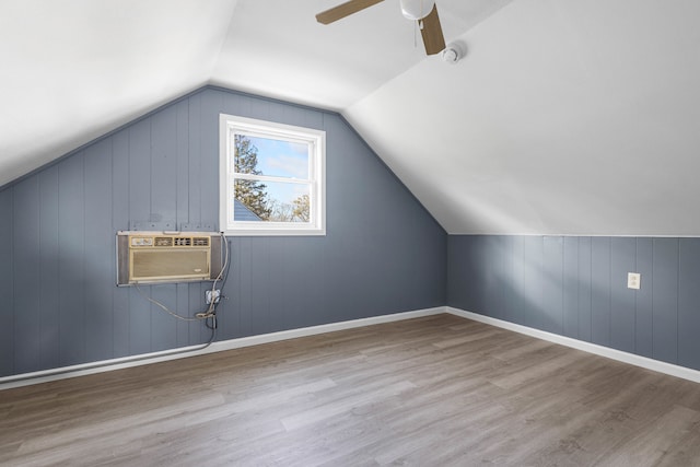 additional living space with light hardwood / wood-style floors, vaulted ceiling, and wooden walls