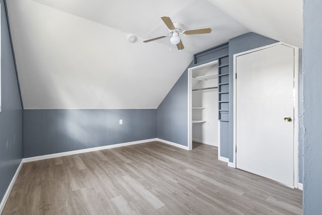 additional living space with built in shelves, light hardwood / wood-style flooring, vaulted ceiling, and ceiling fan