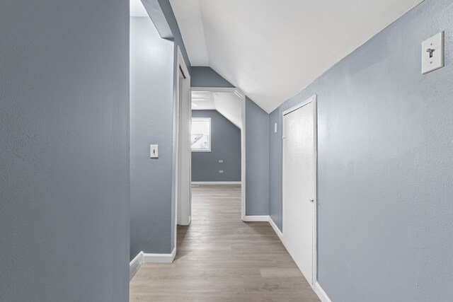 hallway featuring light hardwood / wood-style flooring and lofted ceiling