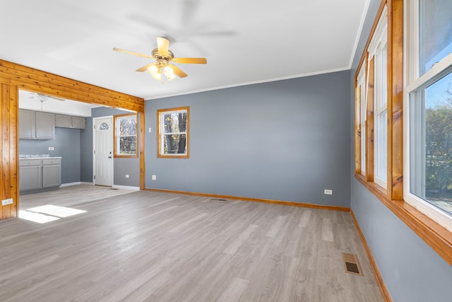 unfurnished living room with plenty of natural light, ornamental molding, and light hardwood / wood-style flooring